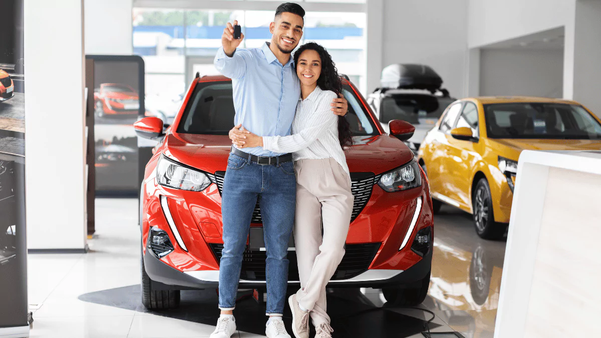 A couple standing in front of a car in a showroom