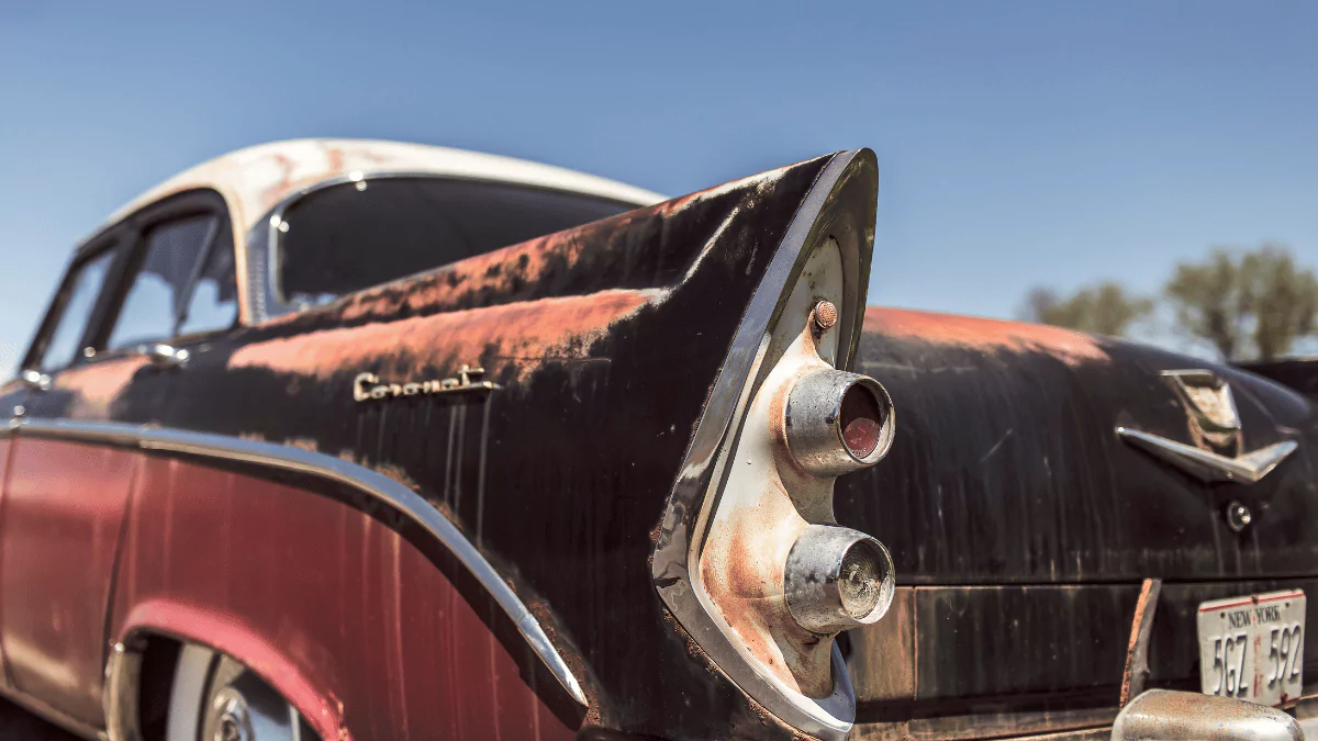 an old rusted car is parked on the side of the road