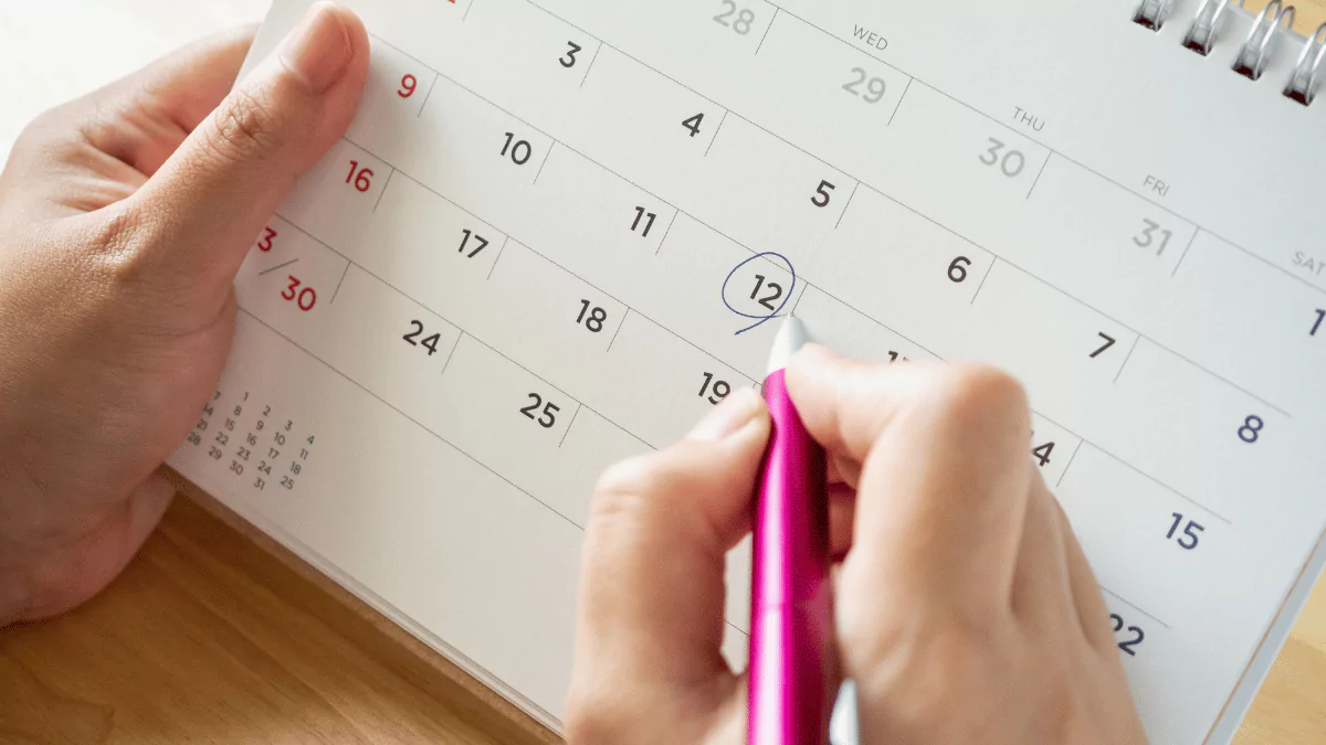 calendar page with a female hand holding a pen on the desk