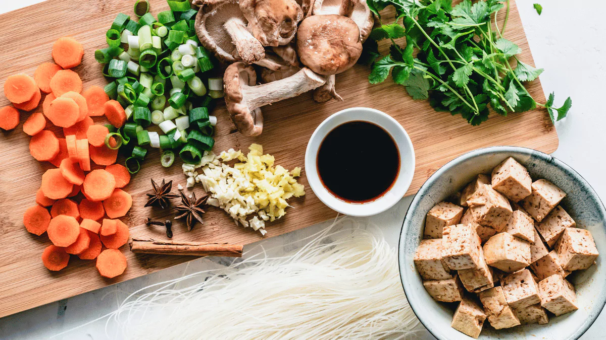 ingredients on a cutting board including tofu, carrots, mushrooms and other vegetables